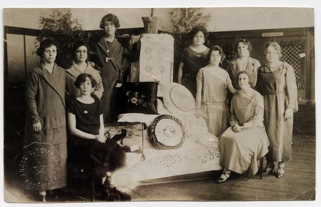 Mujeres junto a exhibición de cojines.