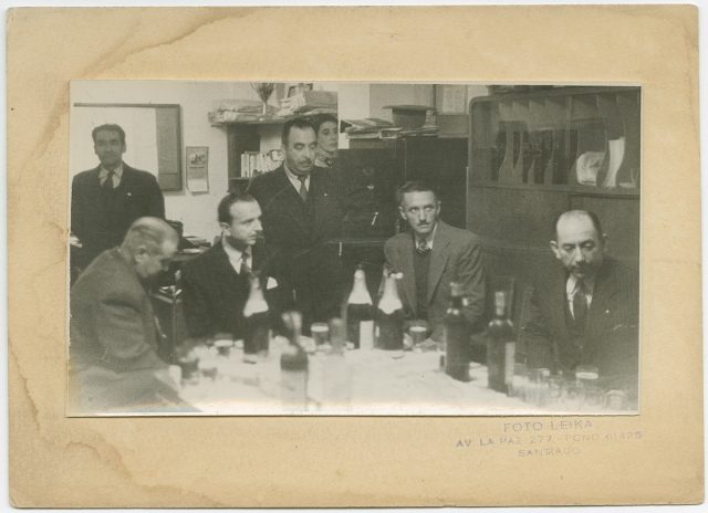 Retrato de hombres alrededor de una mesa.