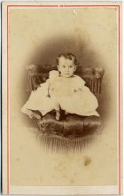 Retrato de un bebé sentada sobre un sillón.