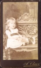 Retrato de bebé sentada sobre un banco.