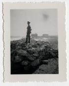 Soldado sobre una contención de roca en la playa