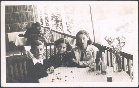Madre con sus hijos sentados a una mesa.