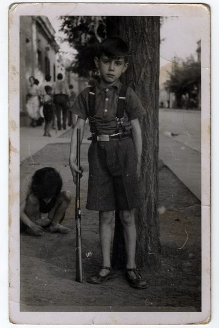 Niño en la calle con escopeta.
