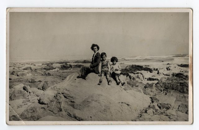Madre con sus hijos sentados sobre una roca.