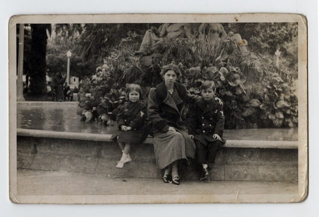 Mujer y dos niños sentados sobre el reborde de una fuente