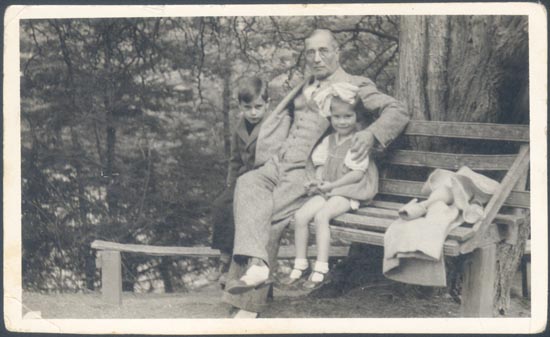 Padre sentado sobre un banco con sus hijos.